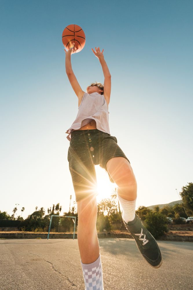 Energetic kid jumping while throwing ball