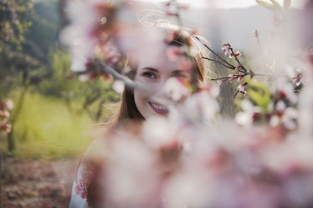Young happy woman between trees in garden