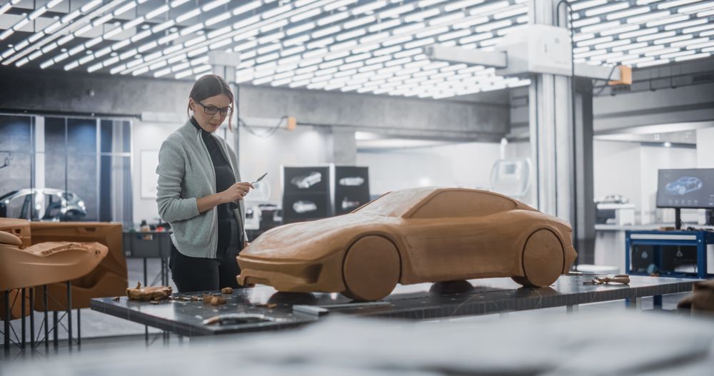 Female Automotive Designer Using a Spatula to Create a Prototype Car Out of Polymer Modeling Clay.