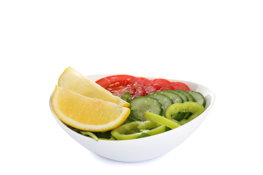 Plate with fresh vegetables slices isolated on plain background