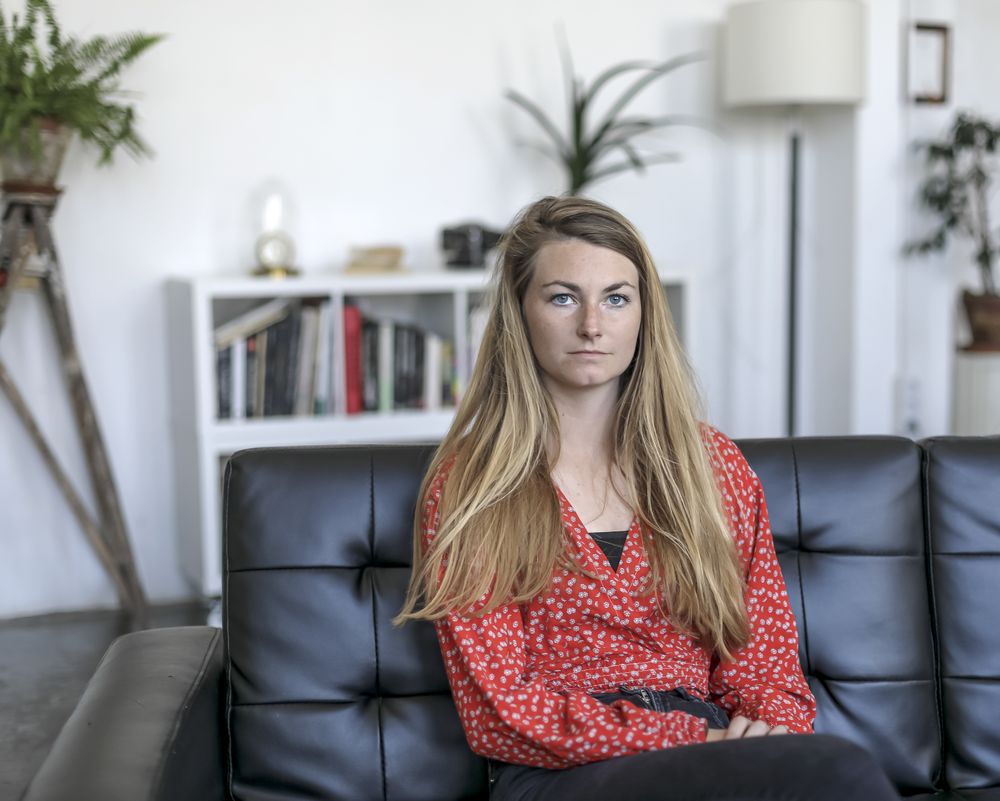 Serious blonde female relaxing on couch at home while looking pensive
