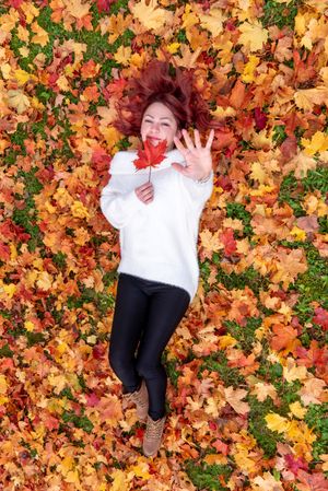 Woman lying back in colorful autumn leaves
