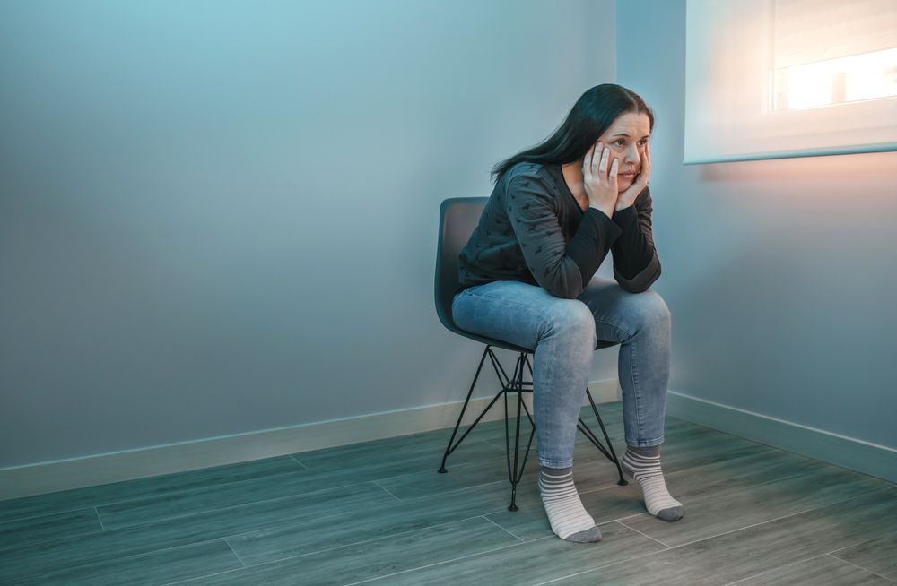 Pensive woman with lost look sitting on a chair