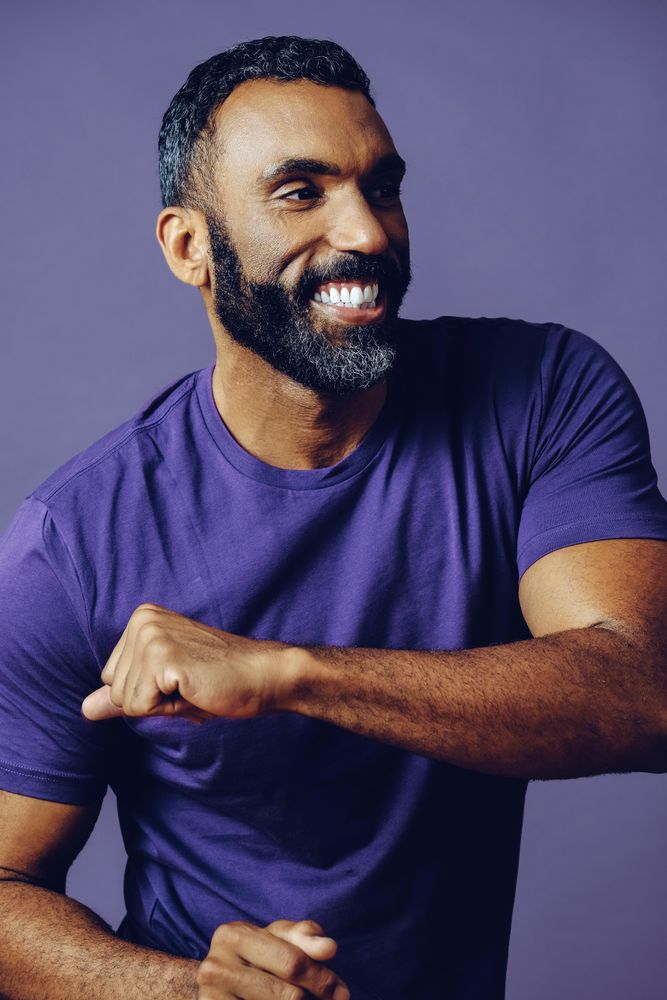 Vertical composition of happy male dancing in purple studio