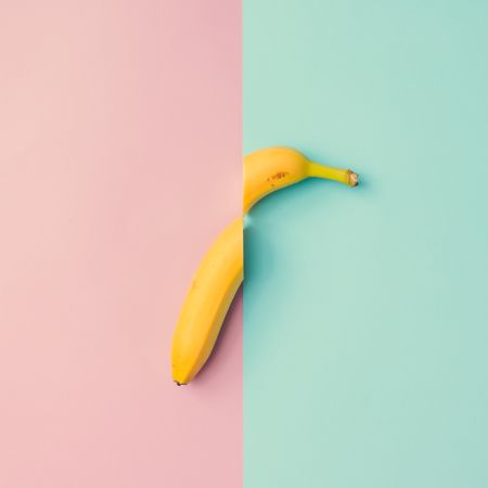 Banana fruit cut in half on pink blue background