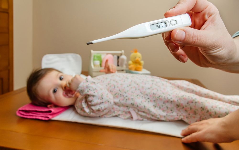 Hands holding thermometer before baby