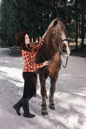 Woman with hat standing beside horse at daytime