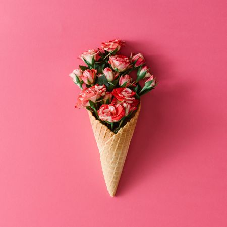 Ice cream cone with colorful flowers on pink background