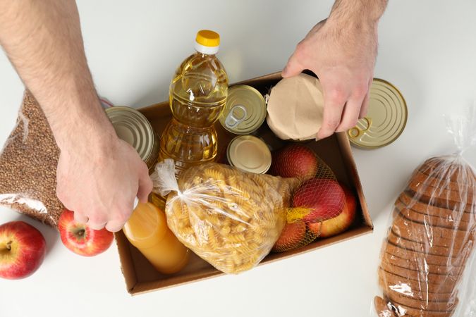 Young man puts groceries in donation box. Volunteer