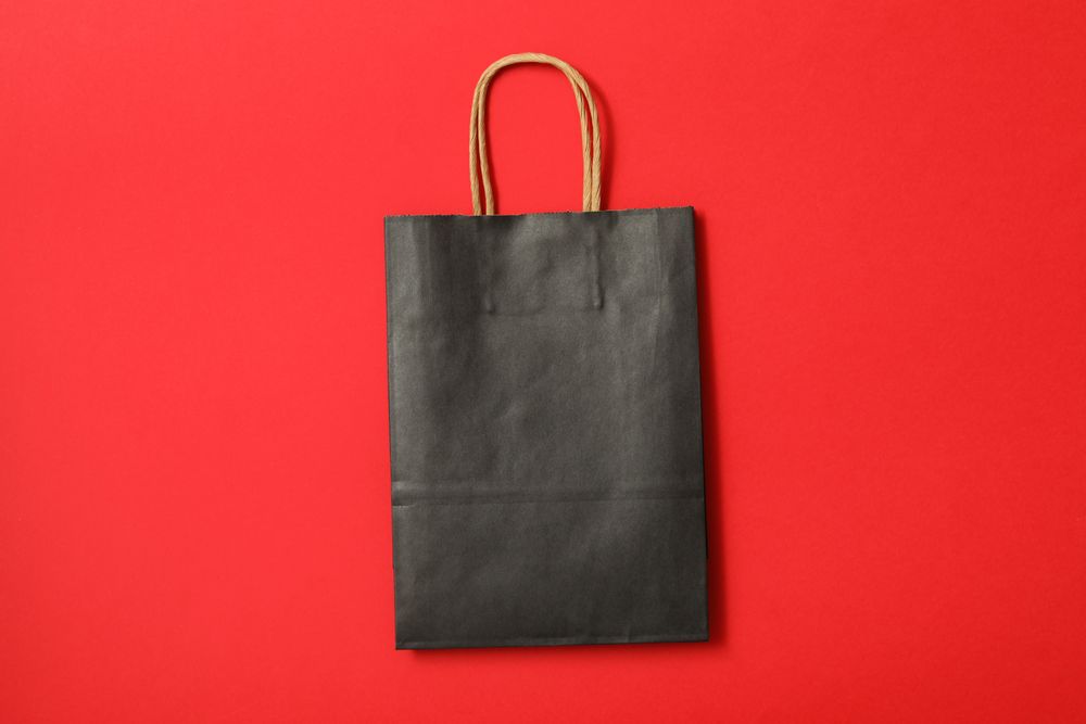 dark paper bag on red background, space for text