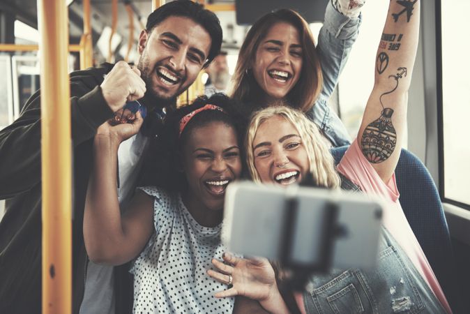 Multi-ethnic group of friends taking selfies on the bus together