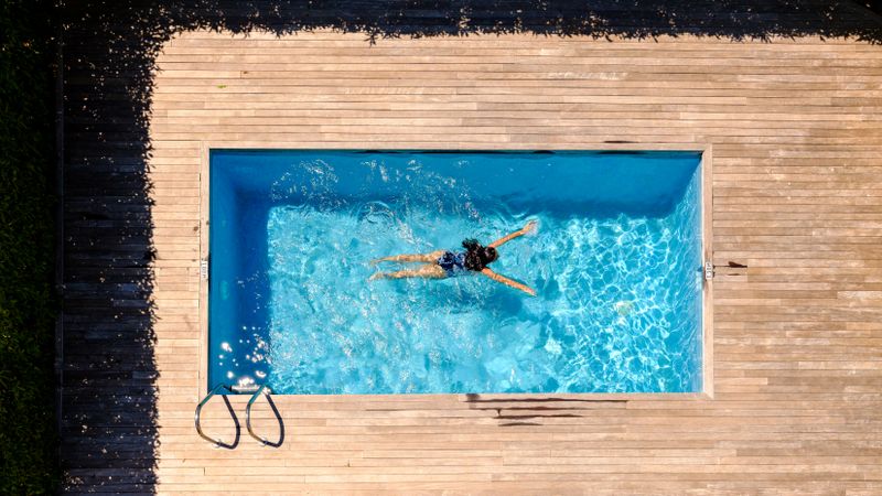 Female swimming in pool water on sunny summer day