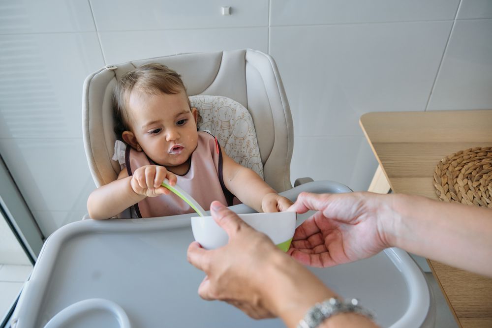 Crop mother feeding daughter in kitchen at home