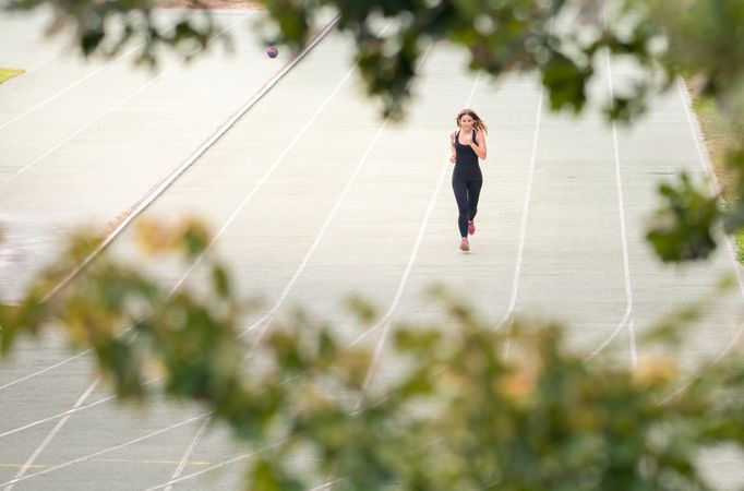 young fit woman running in a track outdoors in a sunny day