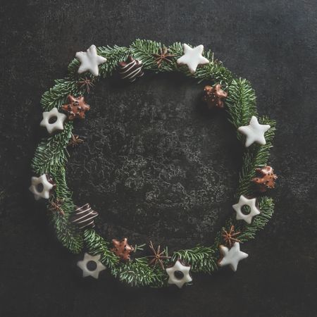 Christmas circle frame made with fir wreath and cookies on dark concrete kitchen table