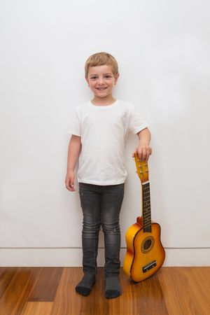 Young blonde boy playing toy guitar