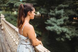 stylish woman sitting on stairs of park in New York smelling flowers