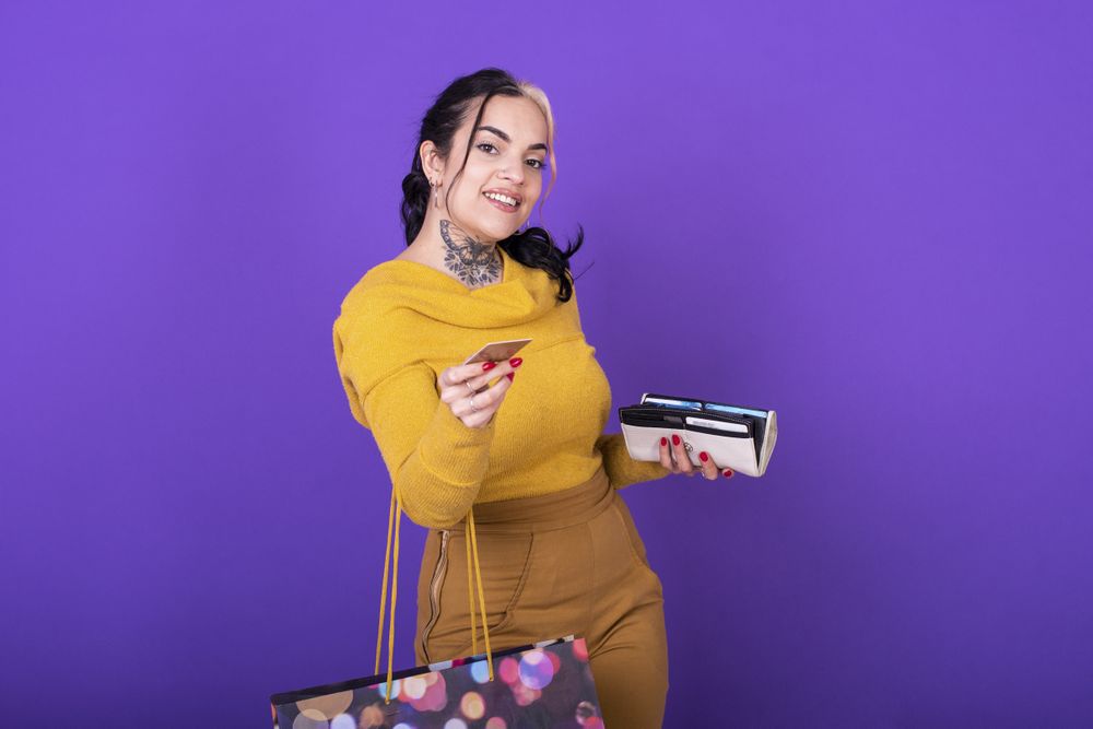 A women holding her wallet and shopping bag while showing a credit card.