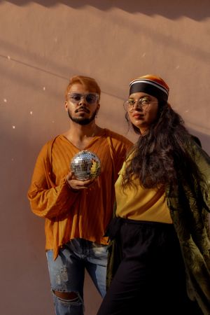 Man and woman wearing casual outfits standing against pink wall