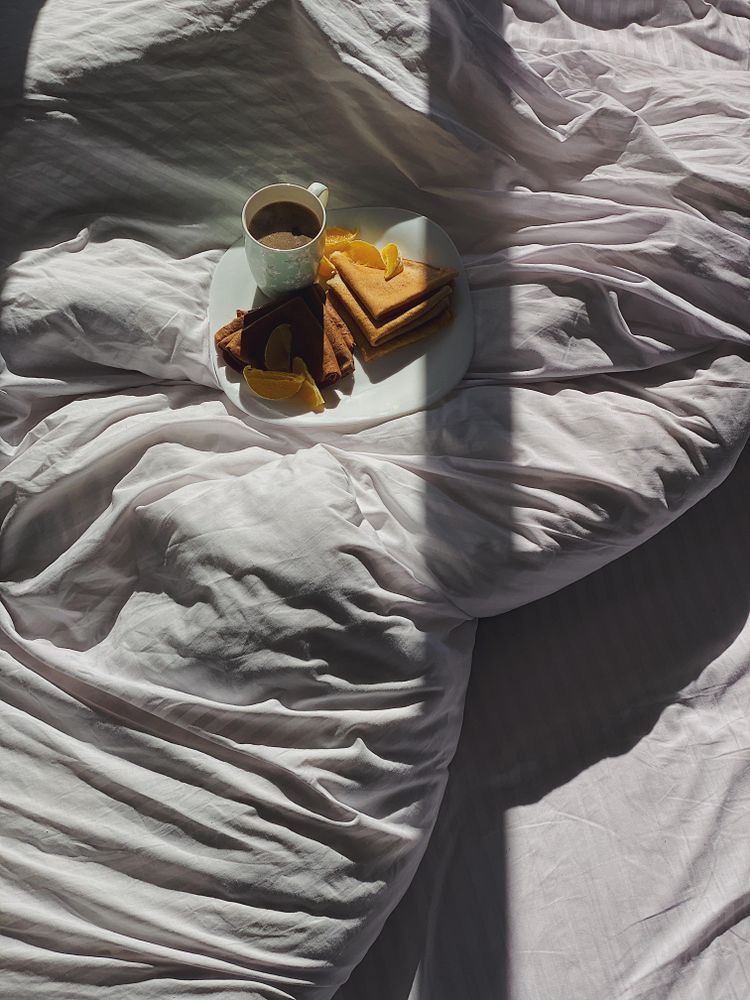 Plate of crepes in bed with coffee