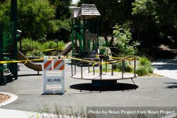 Caution and closed signs around city playground with merry-go-round and slides 0gXW35