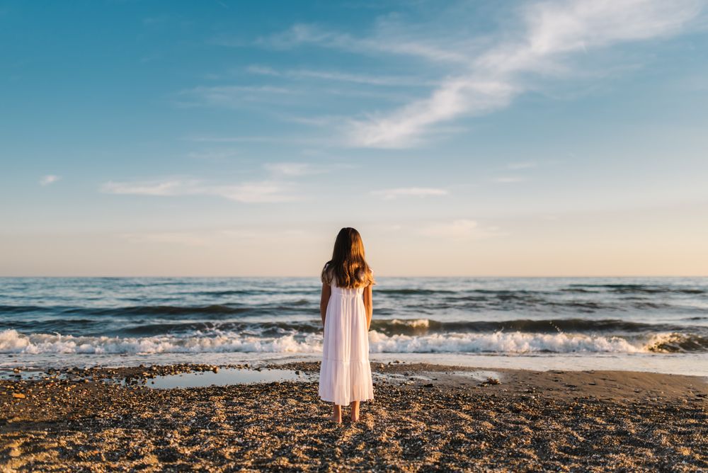 back view girl standing on beach in daylight