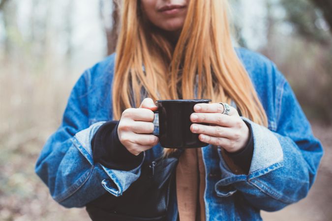 Woman with mug of coffee in the forest