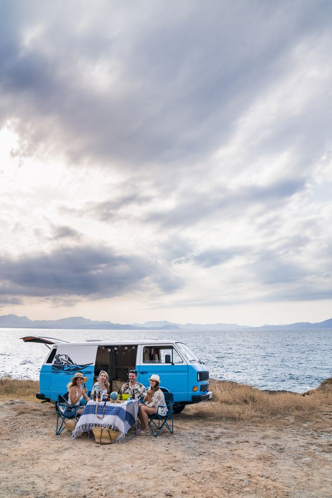 group of friends sitting in chairs next to a minivan