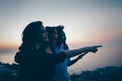 Three close friends looking towards an object of interest with a sense of happiness and surprise