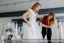 Female making adjustment to wedding gown in fashion designer studio 5rXGnb