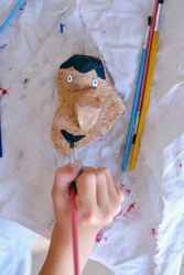 Unrecognizable child painting stone with gouache