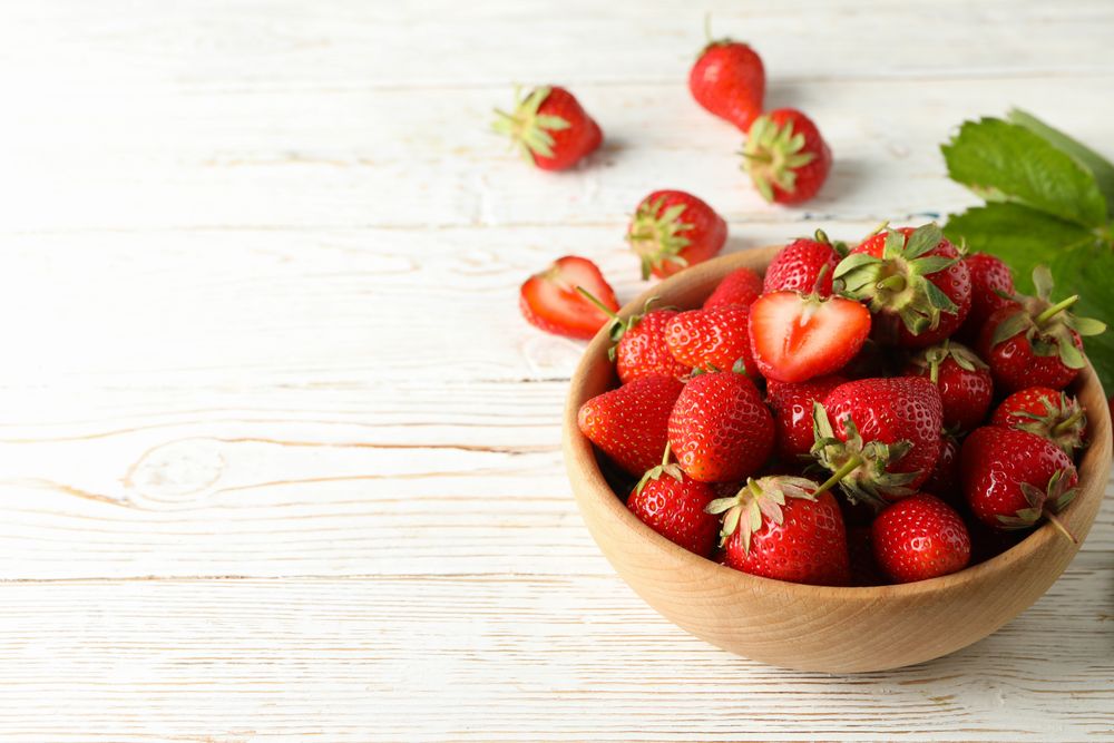 Bowl with tasty strawberry on wooden table. Summer berry