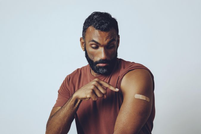 Man pointing at arm to encourage vaccinations, copy space