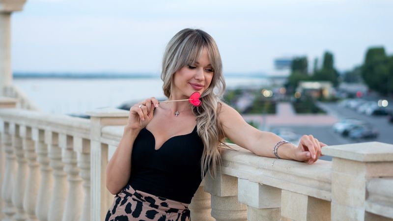 Beautiful young woman with red heart shaped lollipop