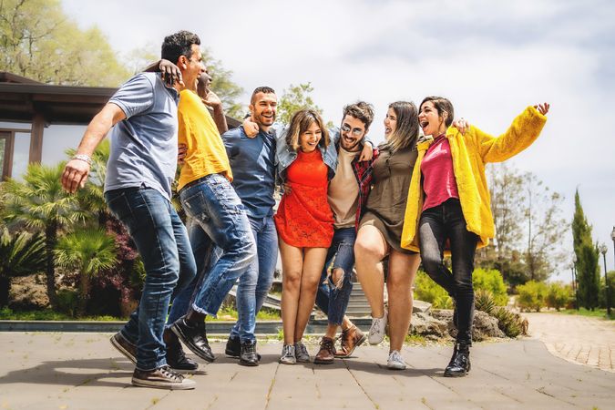Group of multi-ethnic cheerful happy friends hugging and having fun walking together
