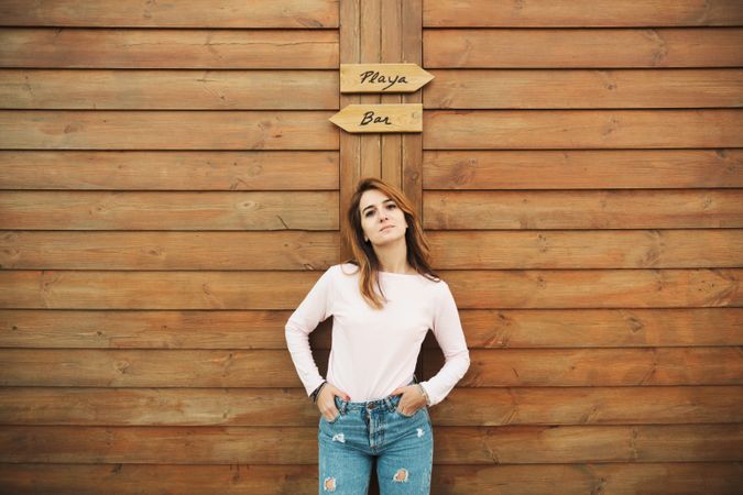 Woman leaning on wooden wall with two signs