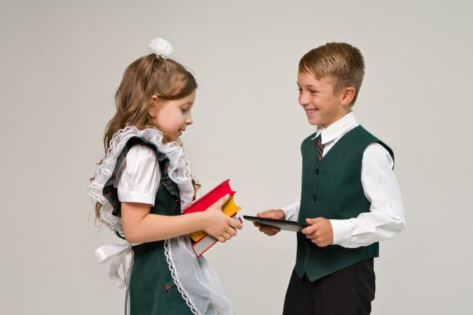 Portrait elementary school students in uniform with books and tablet