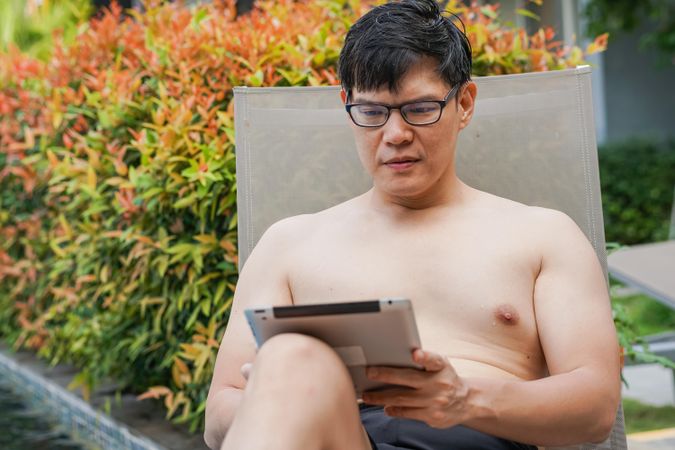 Man concentrating on tablet in lounge chair outside