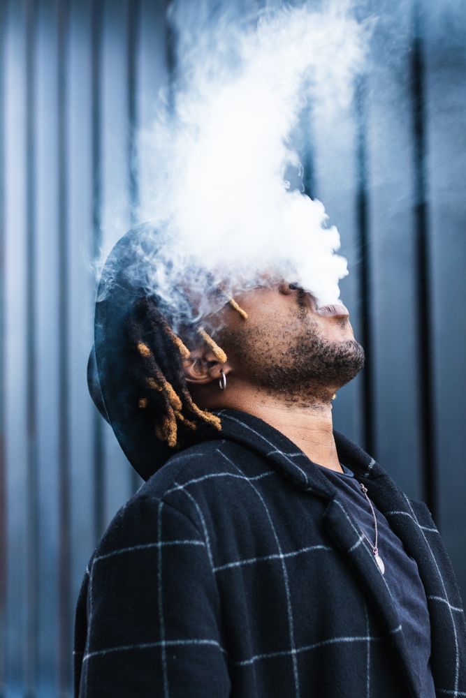 Black man exhaling cloud of smoke on street