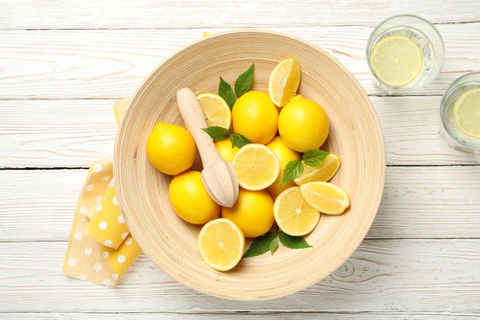 Lemonades and bowl with lemons on wooden background, top view
