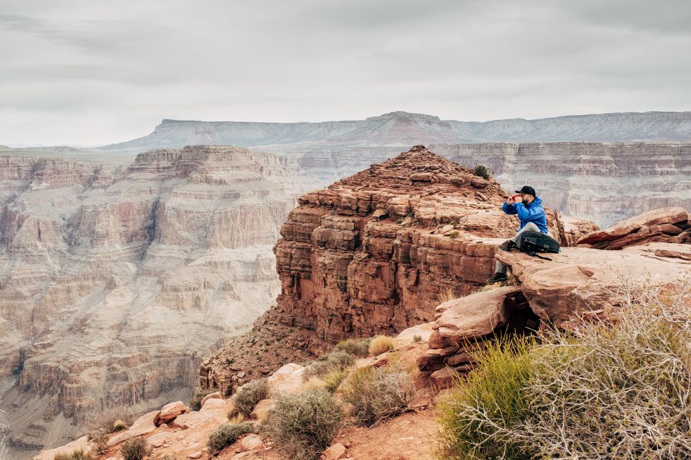 Male having rest on edge of rock and relishing beverage