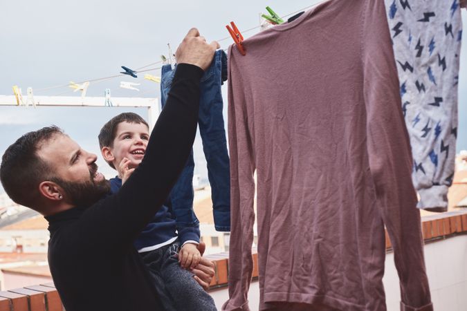 Father and son hanging clothes on rope