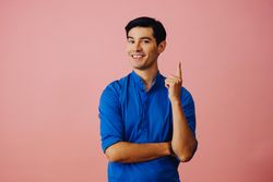 Medium shot of Latino man in pink studio with finger pointed up