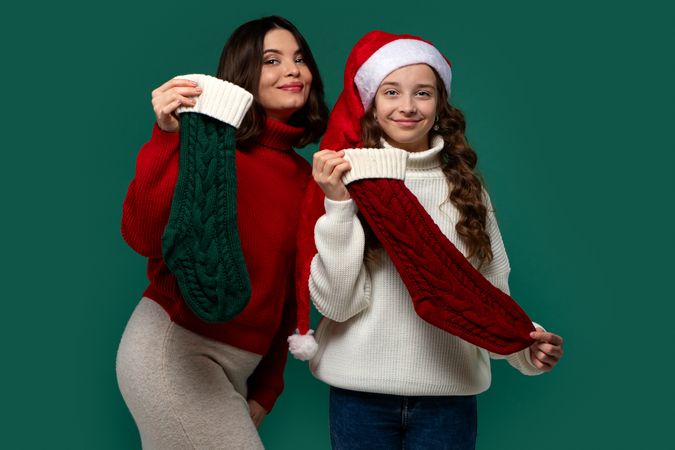 Mum and teenage daughter hold red and green Christmas stockings