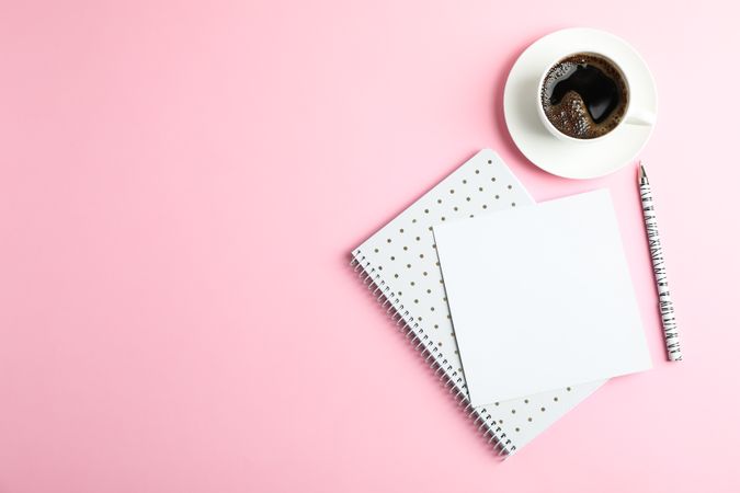 Cup of coffee with copybook and pen on color background, space for text