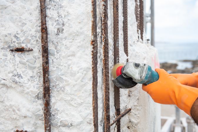 Construction worker with angle grinder polishing rods