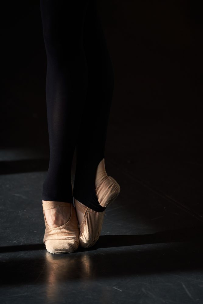 Feet of a professional ballet dancer in a warm-up before rehearsal