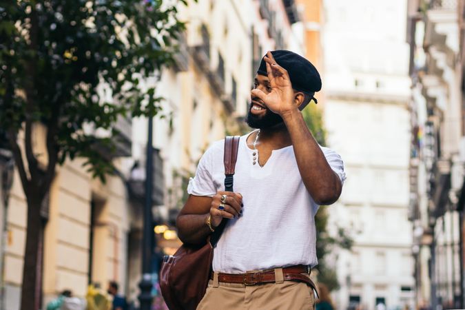Stylish Black man walking on the city street waving someone