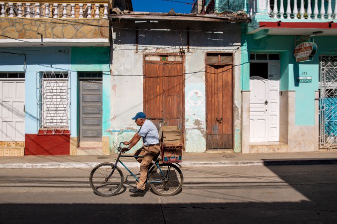 Side view of an older man riding a bicycle on street in Havana, Cuba