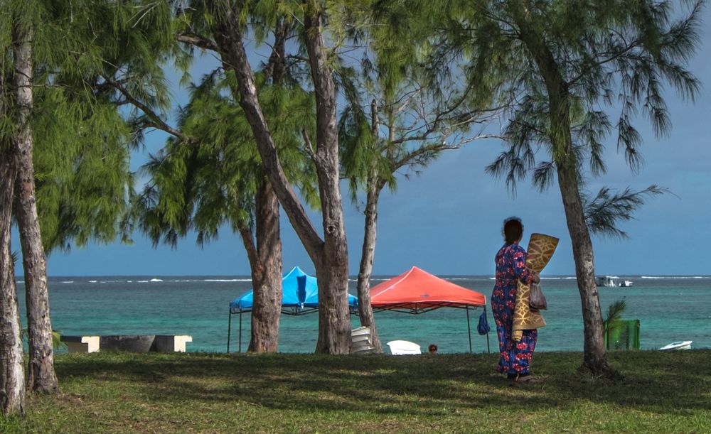 Older woman walking along ocean front with blanket for picnic